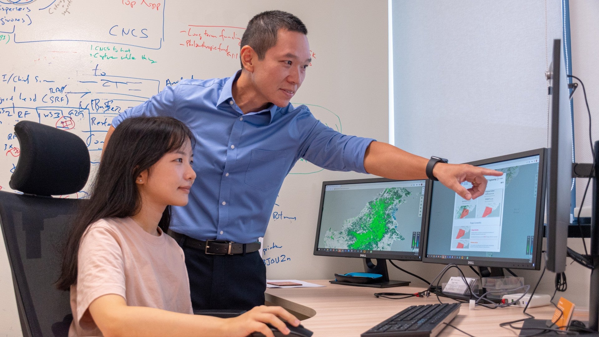 NUS Professor Koh Lian Pin (right) and his research team collaborated with ST Engineering Geo-Insights to develop the Carbon Prospecting Dashboard. The dashboard pictured in the screens helps policymakers and investors identify the location of nature-based projects, and calculate the estimated yield of carbon credits and return-on-investment and quantify the co-benefits of the projects.